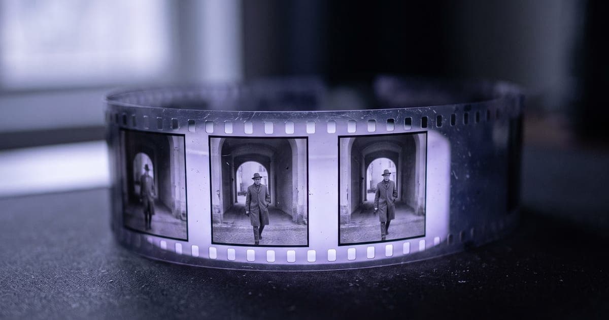 A strip of film curving across a dark surface, four frames of one continuous scene.