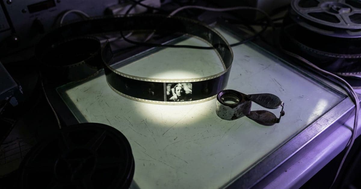 A film strip lying on a light table with one frame highlighted by a soft beam.