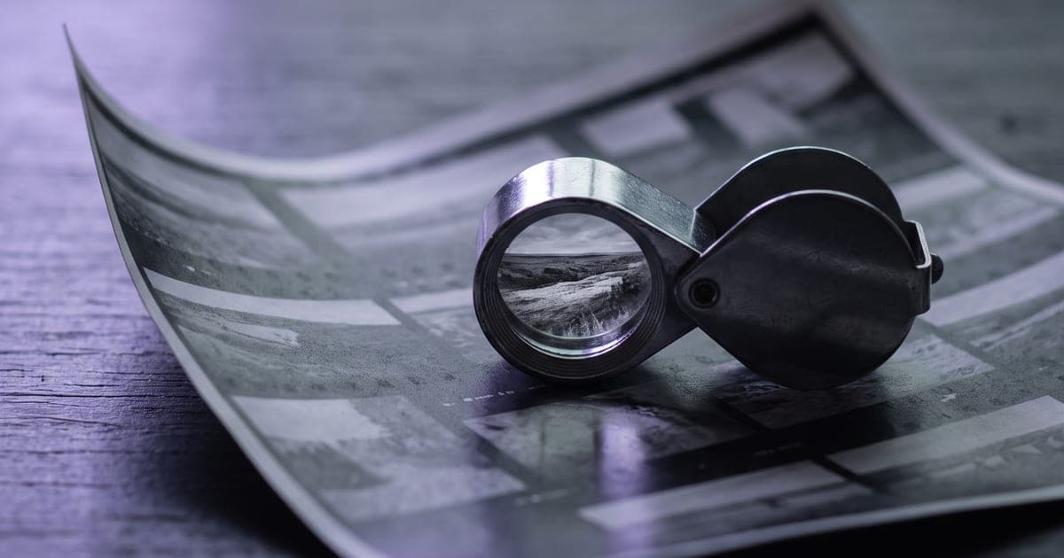 A loupe on a contact sheet, one frame enlarged through the glass.