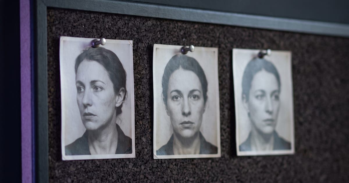 Three printed portraits of the same face pinned in a row on a dark board.