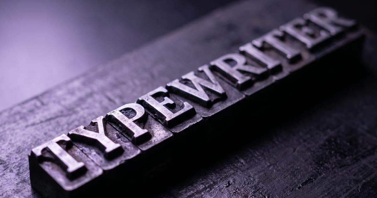 Metal letterpress type arranged in a line on a dark surface.