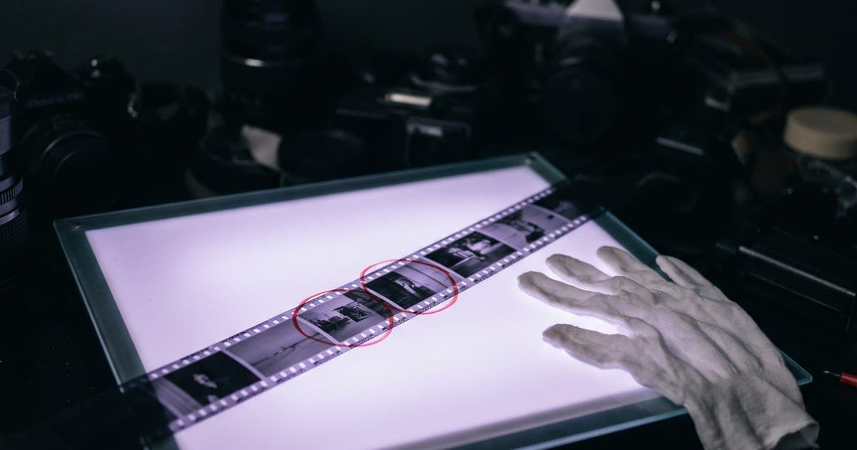 A strip of film on a light box with a few frames marked in red grease pencil.