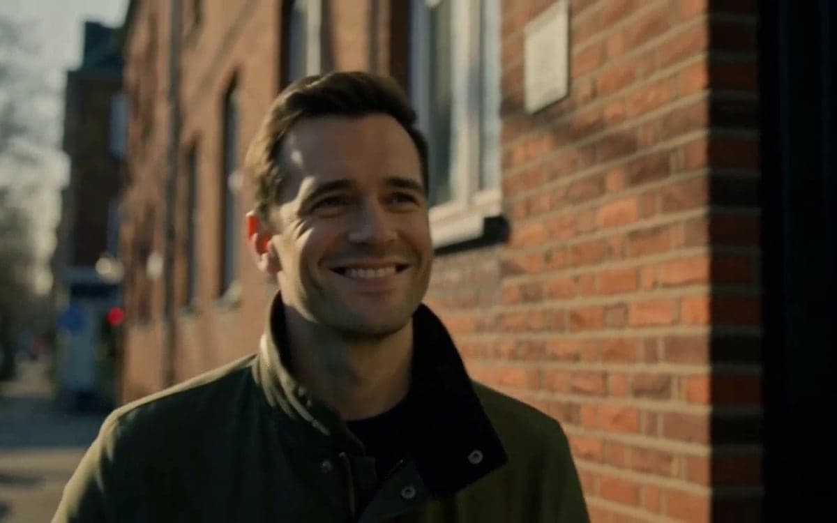 A frame from the extension: the man walks on along the brick wall, in the light of the original clip.