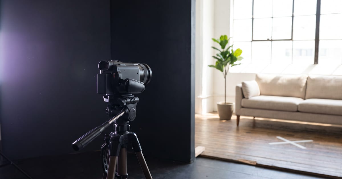 An empty living room seen through a small camera on a tripod, a chalk mark on the floor.