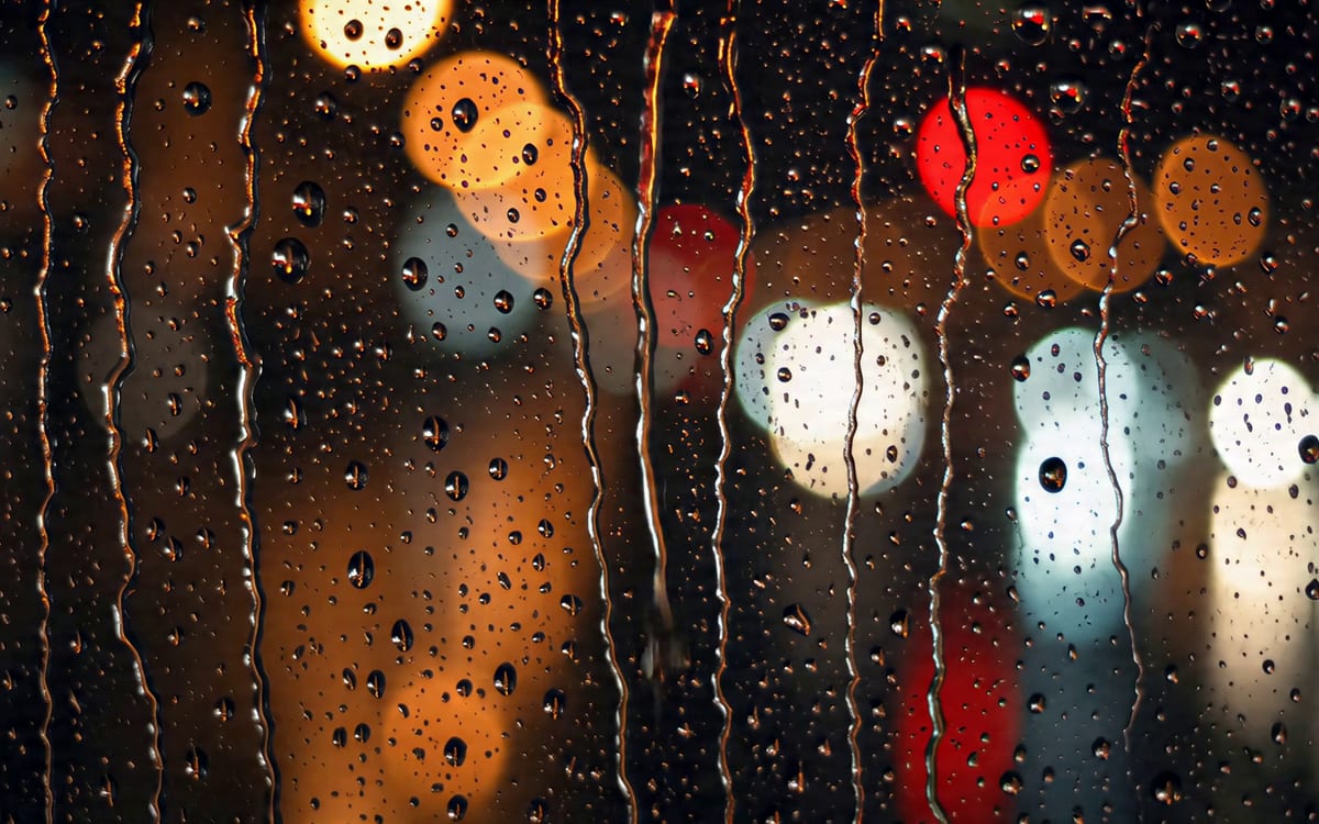 A first frame from a MiniMax clip: rain running down a window at night.